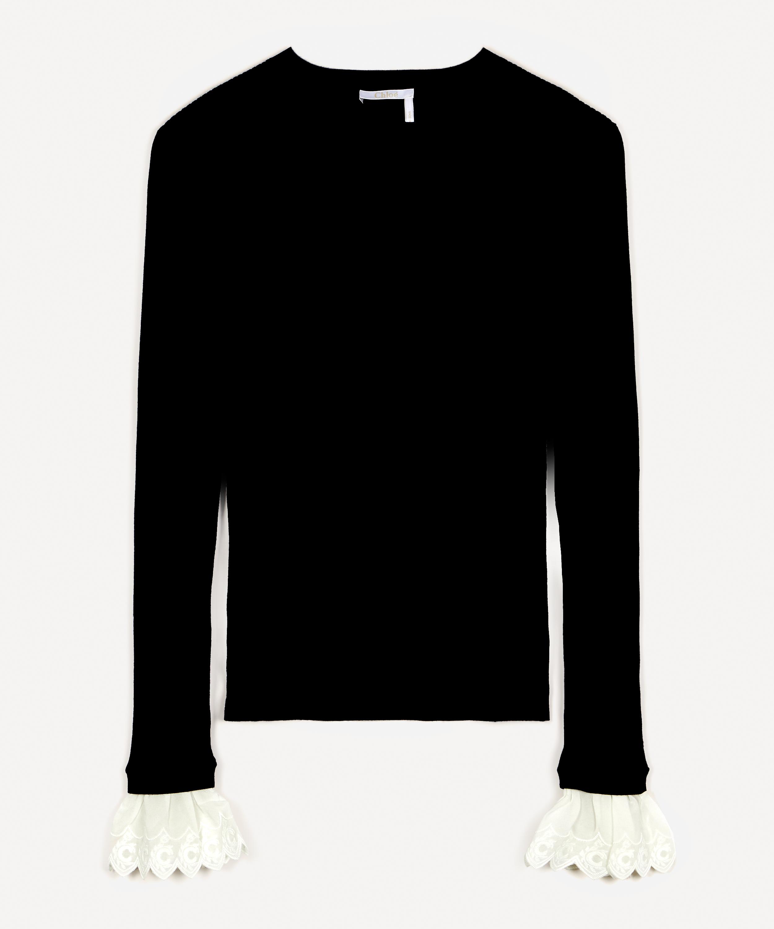 black jumper with white frill cuffs