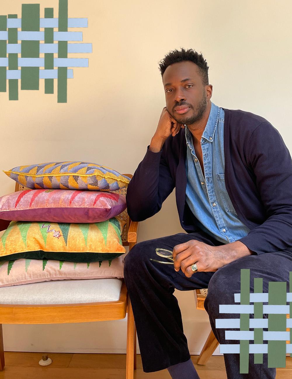 Founder Amechi Mandi at home with a pile of his brand's graphic design cushions