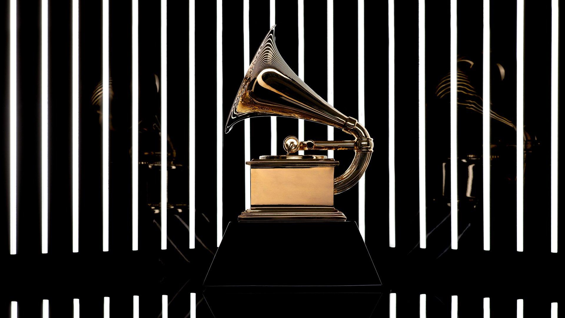 Photo of a gold GRAMMY trophy against a black background with white lights.