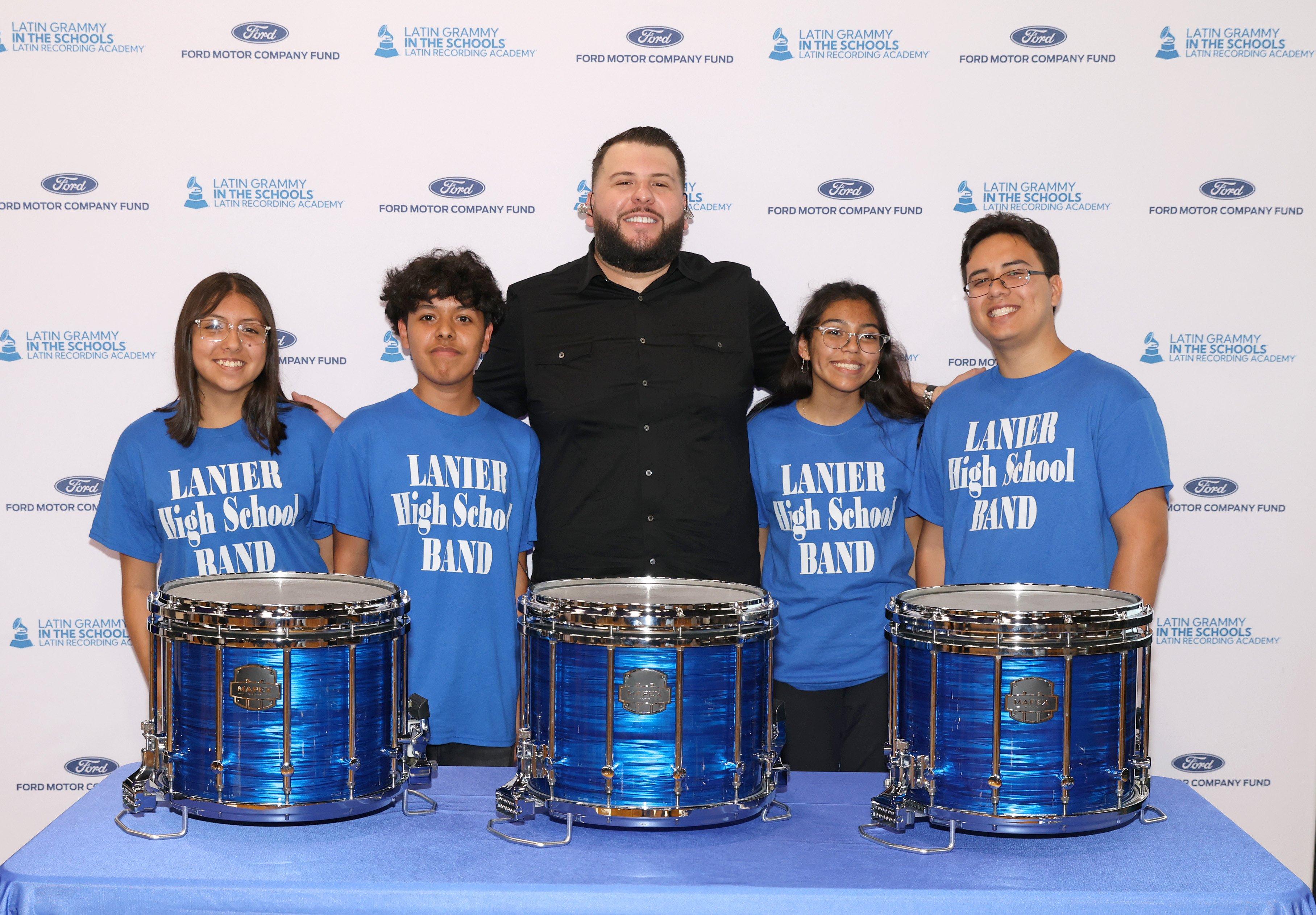 Photo of El Fantasma (C) posing with students at the Latin GRAMMY In The Schools educational program
