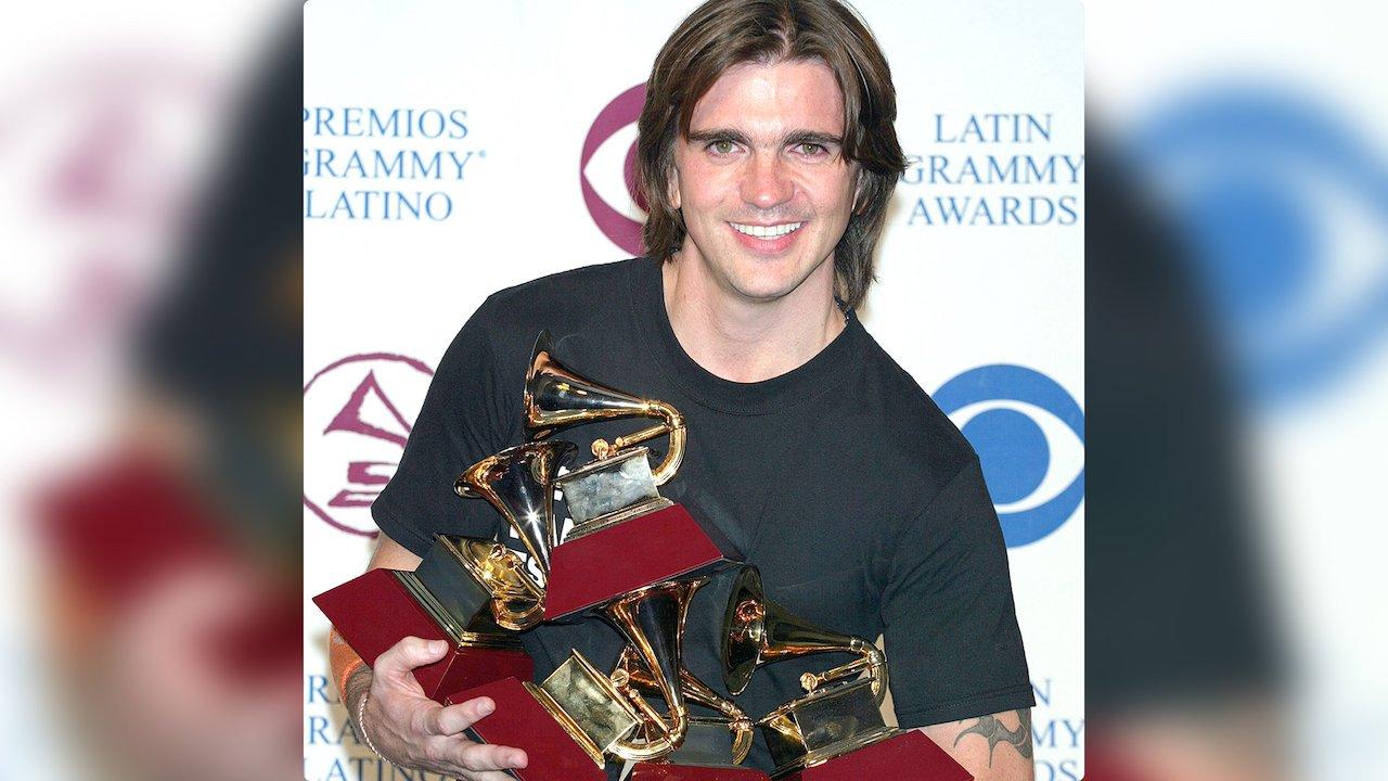 Juanes smiles while holding five GRAMMY awards
