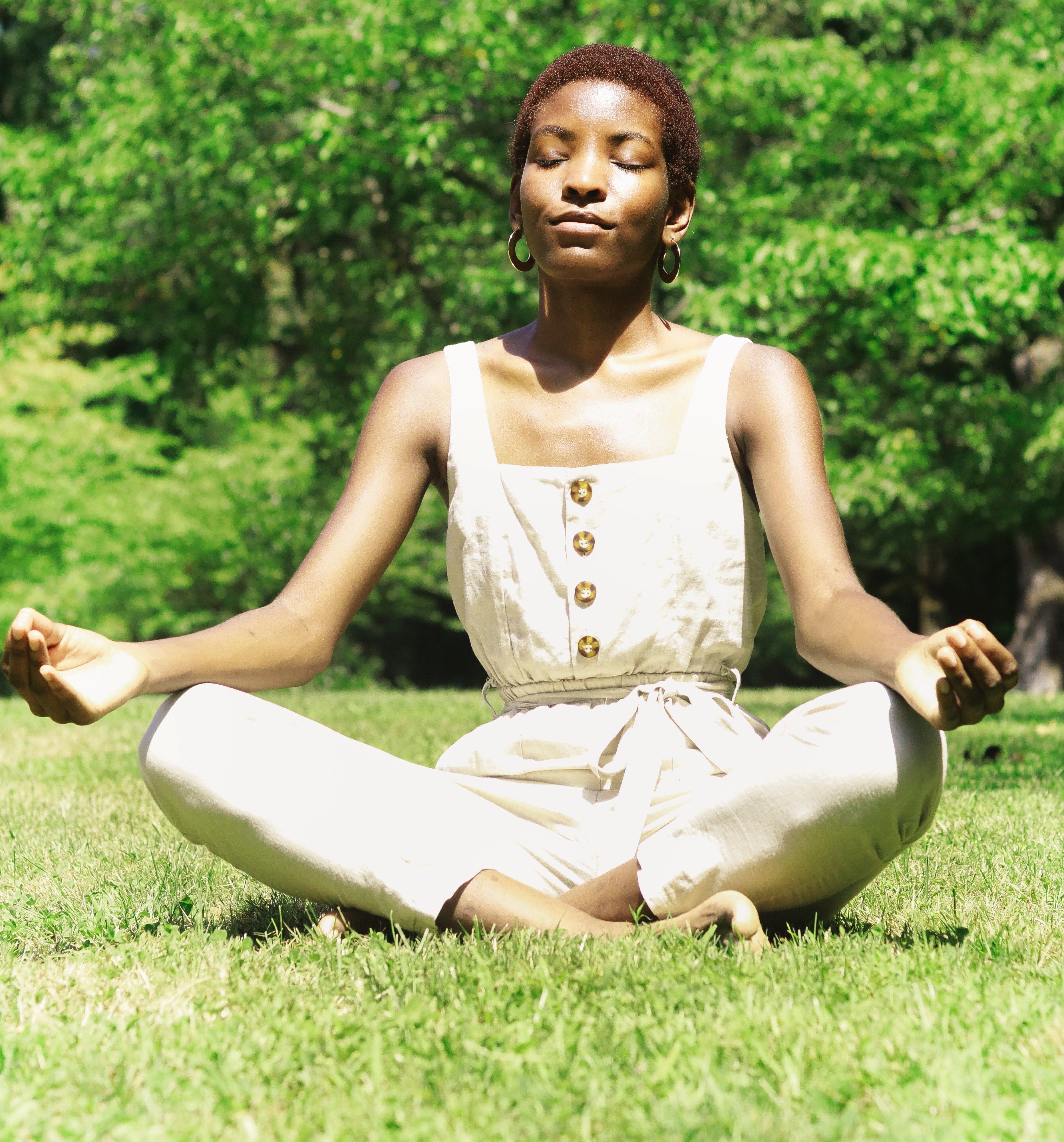 a woman meditates on the grass