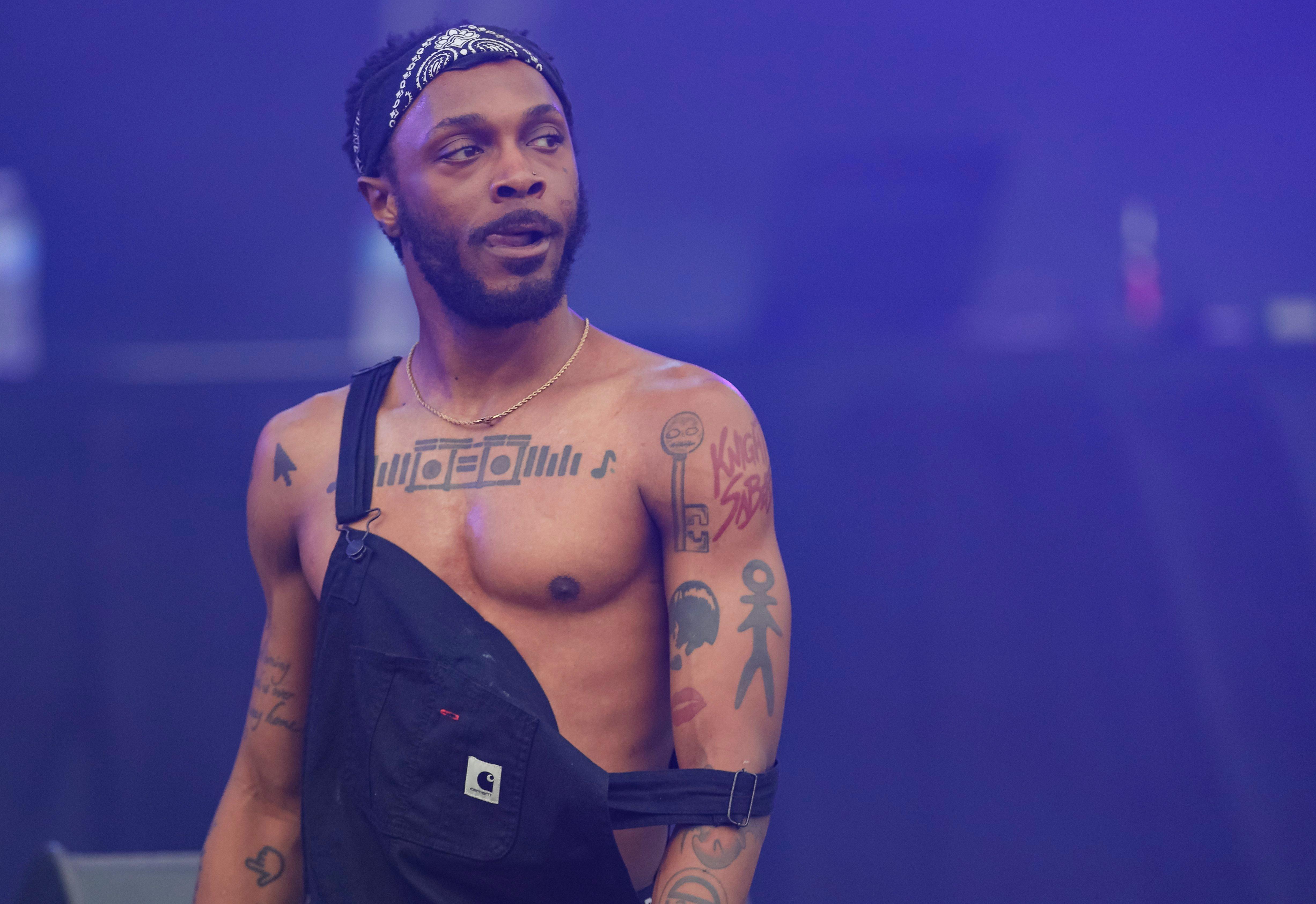rapper JPEGMAFIA poses on stage wearing overalls