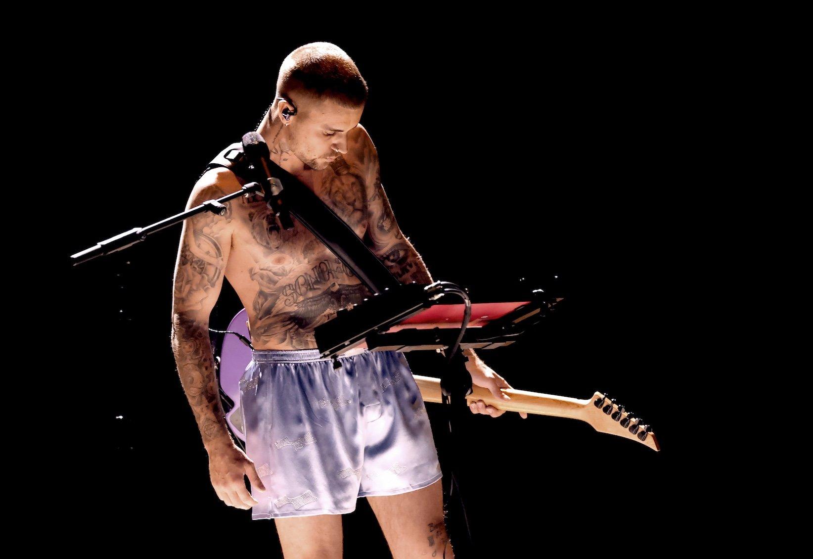 A photo of Justin Bieber performing at the 2026 Grammys. Bieber is on stage wearing only his underwear, holding a guitar and standing in front of a synthesizer keyboard.