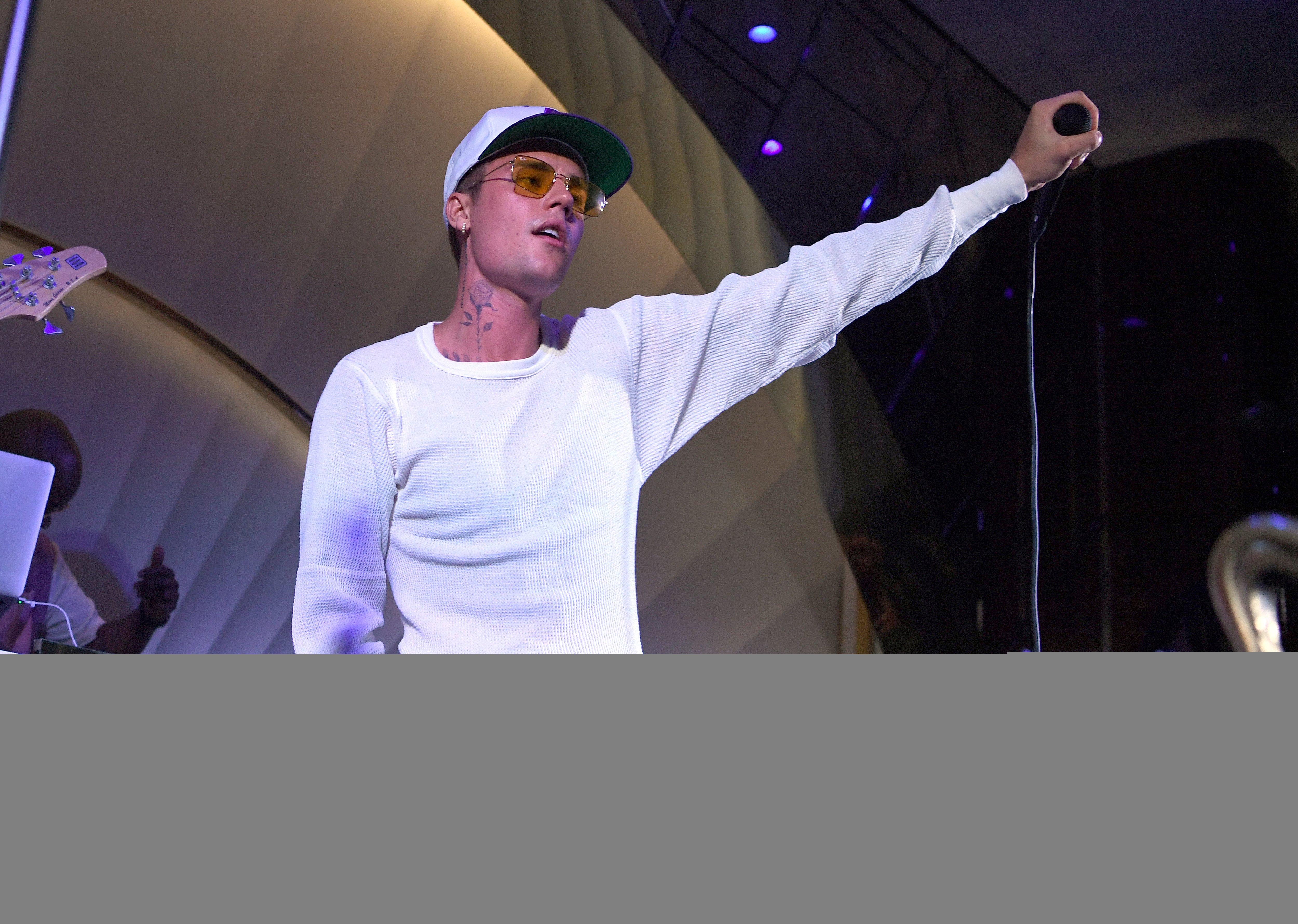 Justin Bieber holds up mic in all-white at July 2021 performance in Las Vegas 