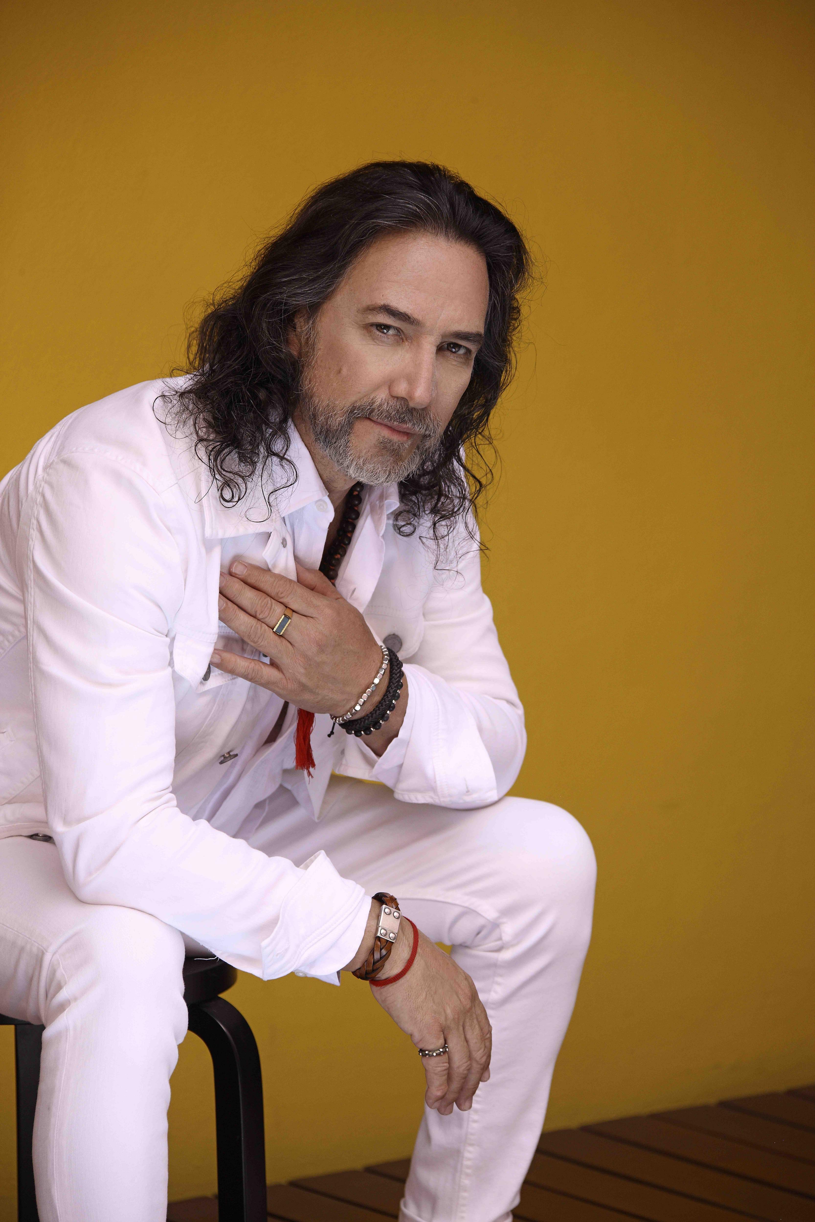 Marco Antonio Solís poses with hand on heart in all-white outfit